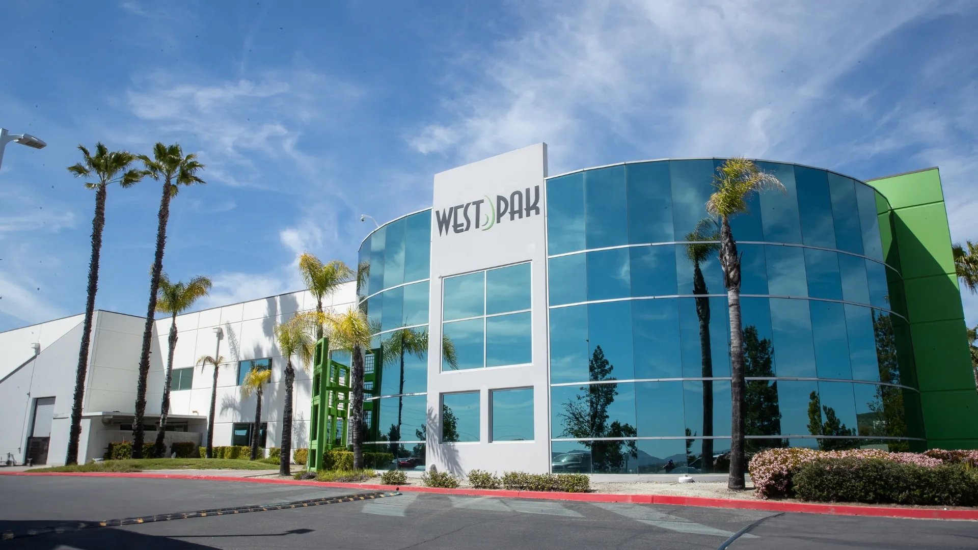 The West Pak headquarters, a curved glass building with palm trees under a blue sky